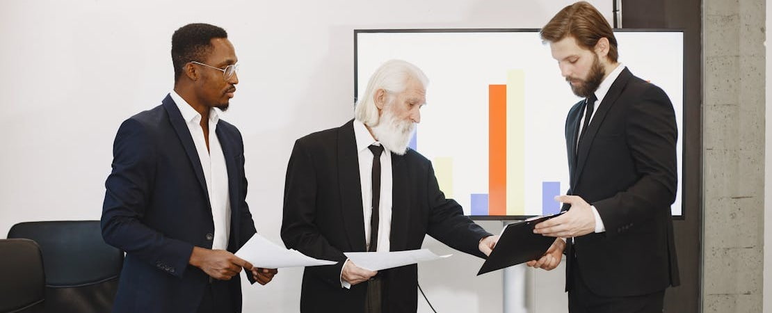 Imagem mostrando três homens em uma reunião de trabalho, representando o curso de inglês profissional.