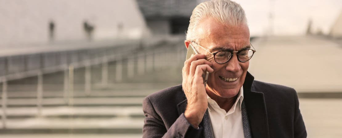 Imagem mostrando um homem usando um celular e um laptop, representando um programa online para praticar inglês.