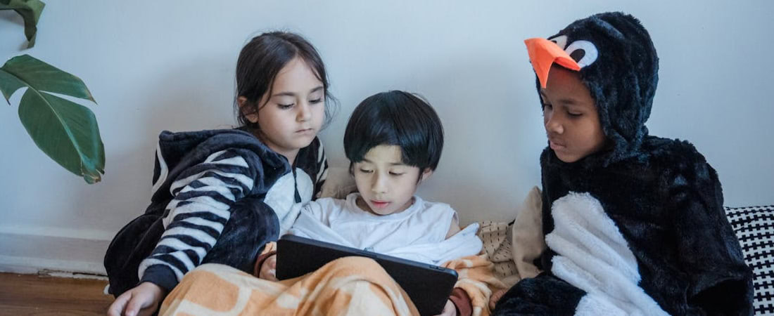 Imagem de crianças entretidas no iPad, refletindo como as crianças podem aprender inglês brincando.