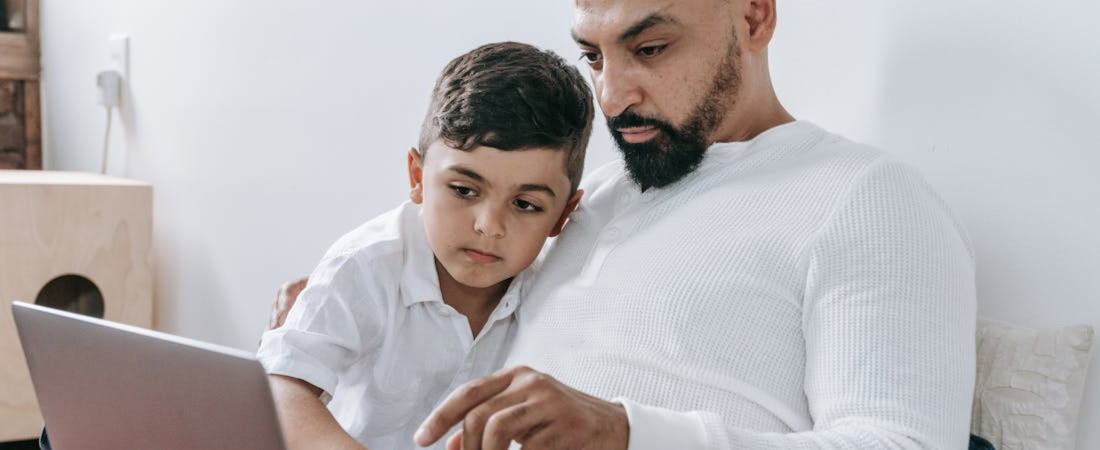 Imagen de pai e filho sorrindo em frente ao laptop, mostrando na prática como acompanhar aprendizado de inglês dos filhos de forma divertida e participativa.