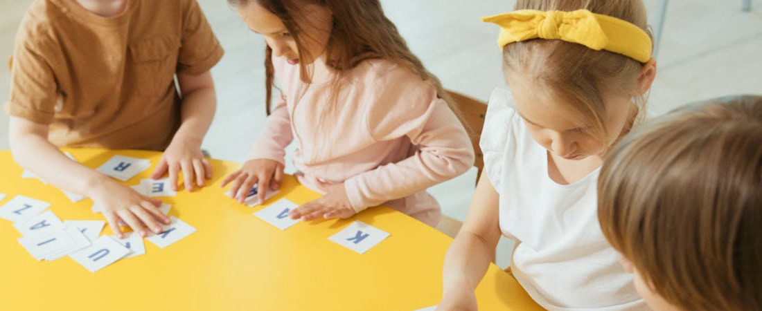 Imagem de crianças brincando com letras, mostrando atividades divertidas para crianças aprenderem inglês.