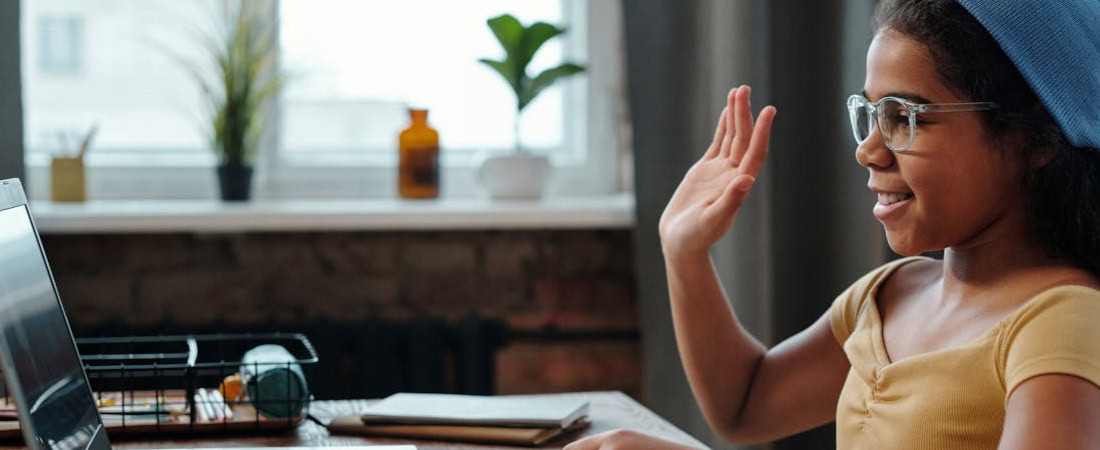 imagem da menina sorridente falando com confiança em frente ao laptop, refletindo os resultados de desenvolver conversação em inglês para crianças